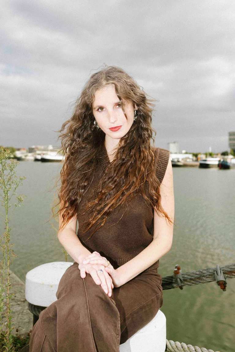 Portrait of Lisaboa Houbrechts sitting at a river and looking into the camera.